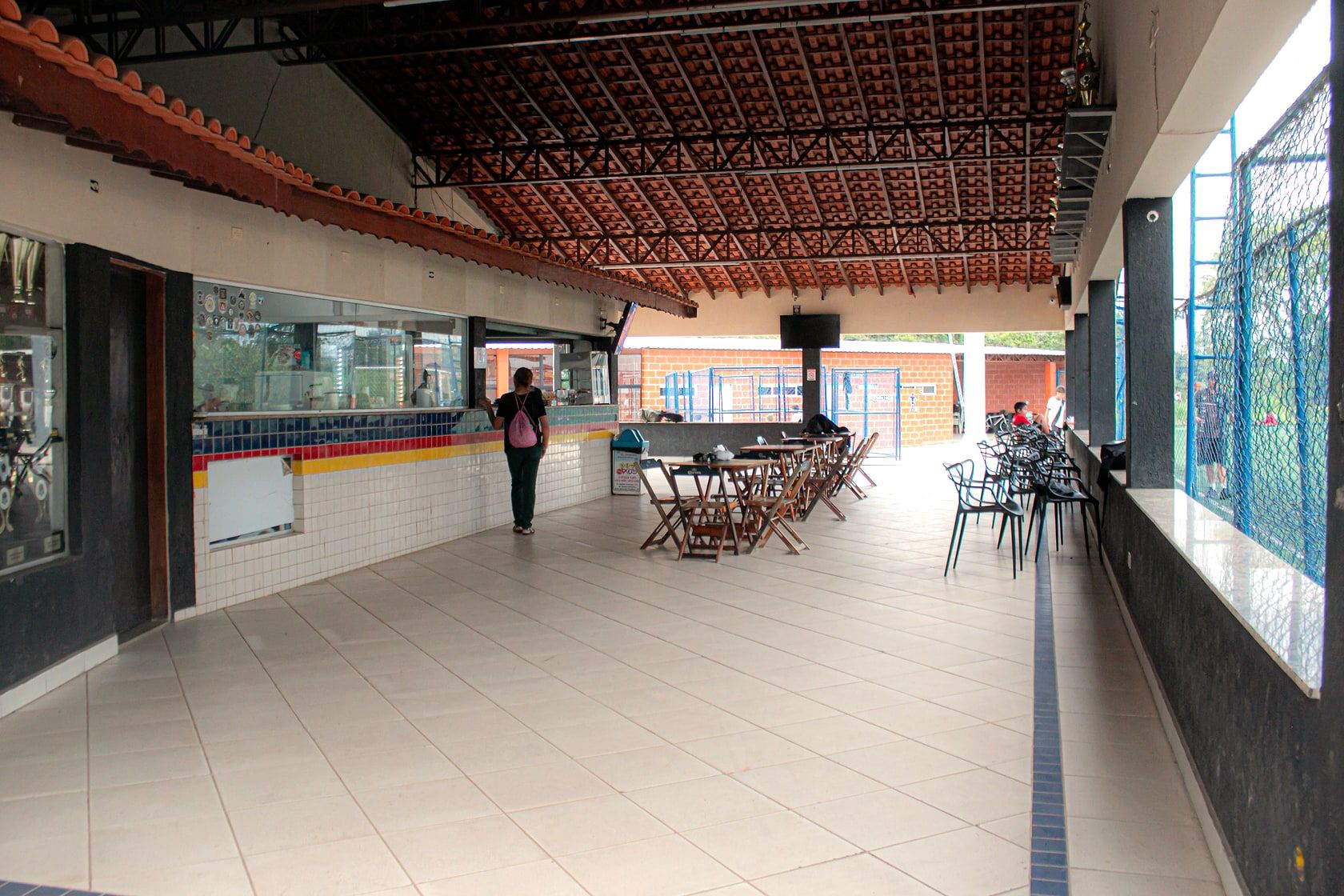 Bar do Capela Beach: balcão de azulejos, troféus e mesas no salão coberto
